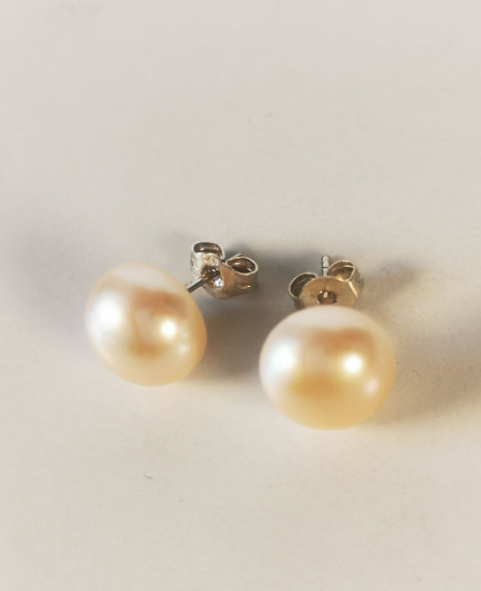 Boucles d'oreilles perles de culture couleur champagne, 10.5mm, montées sur clous argent. Présentées cote à cote , perles en bas, clous inclinés un peu à gauche. Vue de face haut.