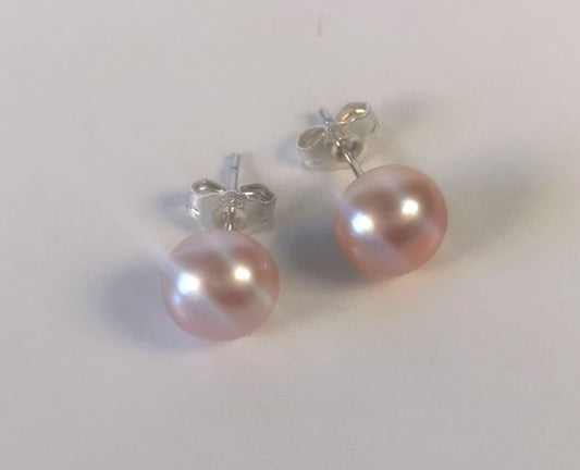 Boucles d'oreilles perles de culture parme, 8.5mm, montées sur clous argent. Présentées cote à cote , perles en bas, . Vue de face haut.