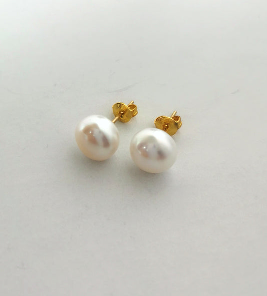Boucles d'oreilles perles de culture blanches 9mm montées sur clous plaqués or. Présentées cote à cote, perles en bas, posées sur un fond blanc. Vue de face.