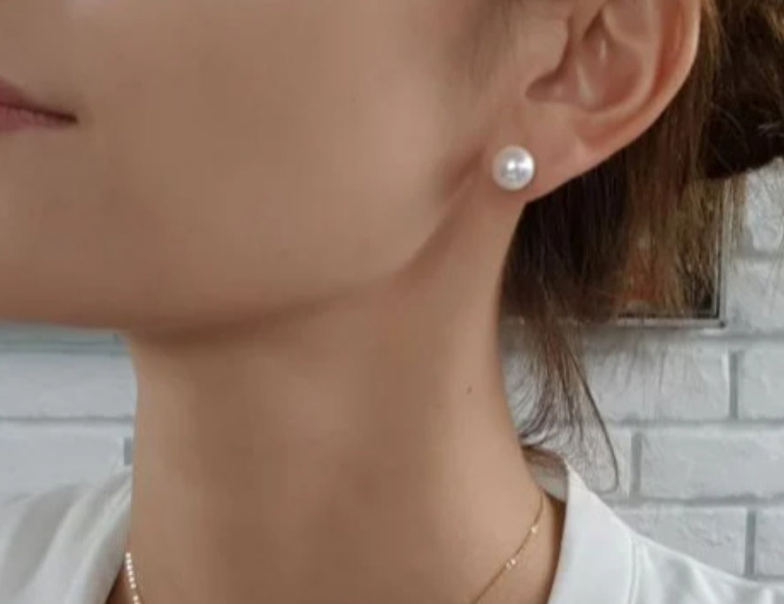 Boucles d'oreilles perles de culture blanches 9mm montées sur clous plaqués or. Présentation d'une boucle sur un oreille de femme. Vue de trois quart  face.