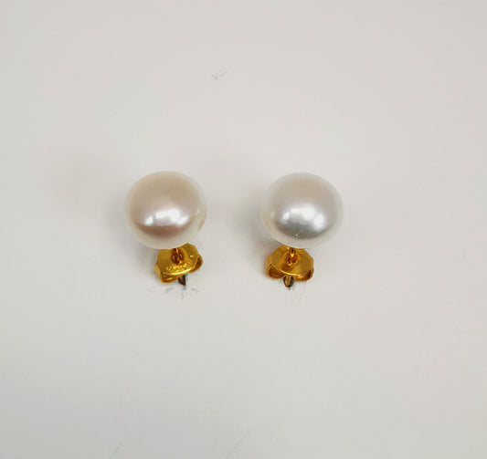 Boucles d'oreilles perles de culture blanches 7.5mm montées sur clous plaqués or. Présentées cote à cote, plantées sur un fond blanc, orientées vers l'arrière ce qui permet de voir les fermoirs dessous. Vue de dessus.