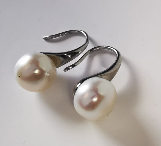 Boucles d'oreilles perles de culture blanches 9mm, montées sur pendants argent larges. Les boucles sont présentées cote à cote, perles en bas , pendants inclinés vers la droite. Vue de face  haut.
