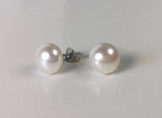 Boucles d'oreilles perles de culture blanches 7mm montées sur clous argent. Les boucles sont présentées cote à cote, celle de gauche inclinée ce qui permet de voir le clou argent sur sa droite. Vue de face