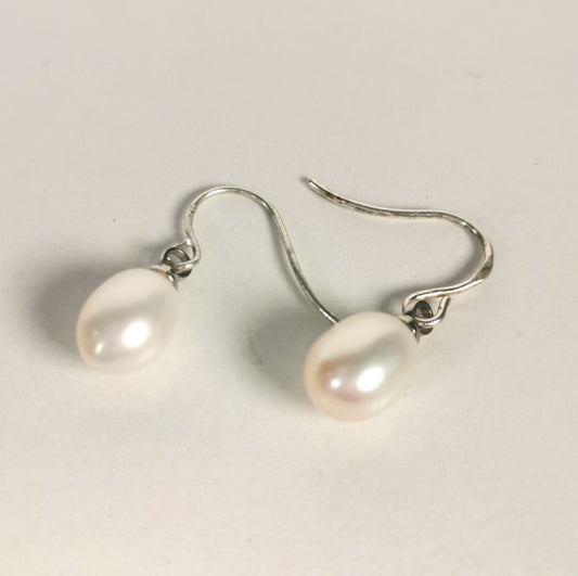Boucles d'oreilles perles blanches ,ovales 7-9mm, montées sur pendants argent, posées sur un fond blanc, cote à cote, pendants se faisant face, les 2 boucles inclinées de 45 degrés vers la droite. Vue de dessus.