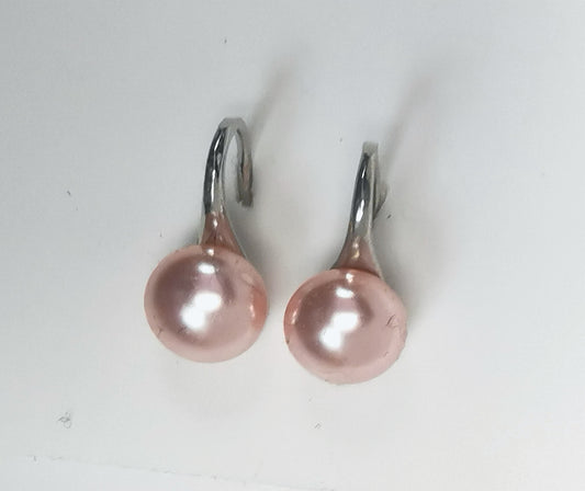 Boucles d'oreilles composées de perles de culture roses 8.5mm sur pendants argent épais. Présentées à plat sur un fond blanc, cote à cote. Vue de dessus.
