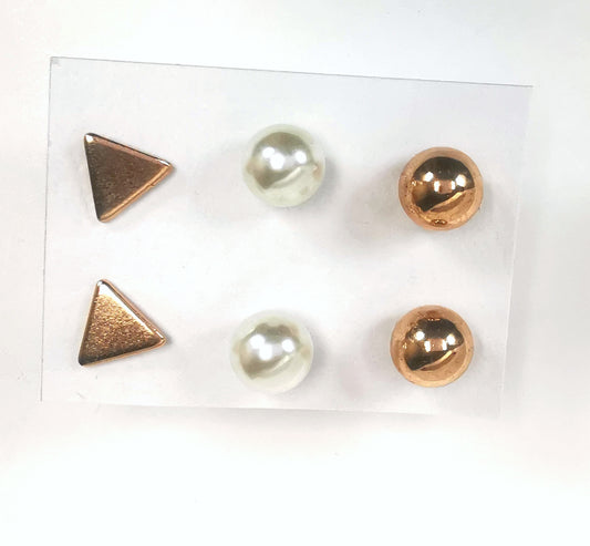 Trios de boucles d'oreilles clous fantaisie, la première est un triangle doré, la deuxième une perle fantaisie et la troisième une sphère dorée. Présentées plantées sur un fond blanc, vue de dessus.