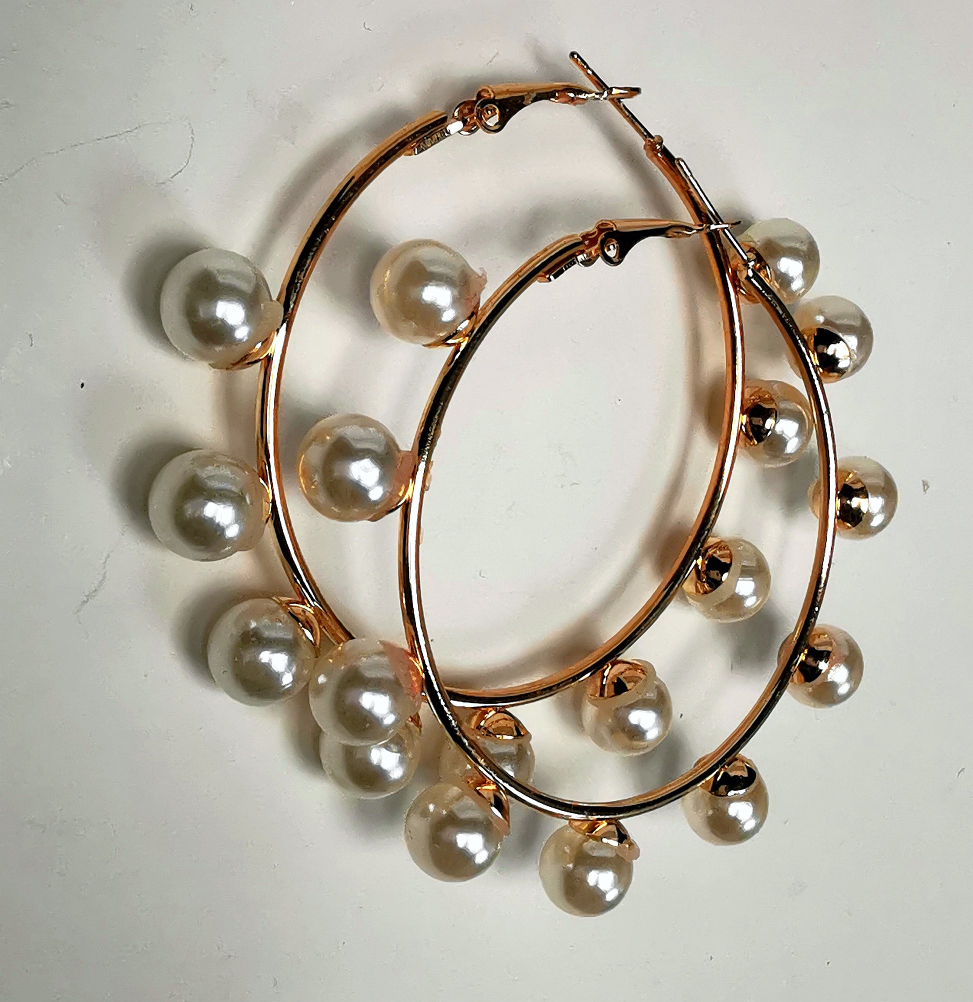 Boucles d'oreilles créoles et perles, diamètre 35mm, fil 1.5mm avec 9 perles de 8mm sur la périphérie. Présentées posées sur un fond blanc, l'une sur l'autre , vue de gauche.