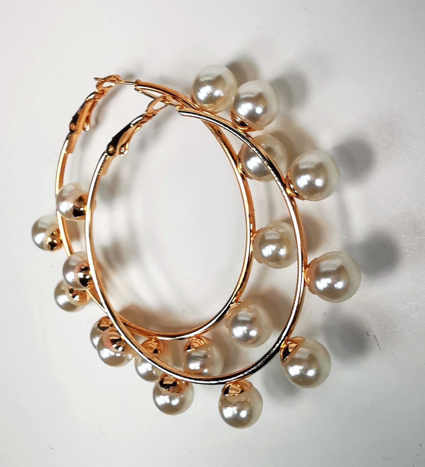 Boucles d'oreilles créoles et perles, diamètre 35mm, fil 1.5mm avec 9 perles de 8mm sur la périphérie. Présentées posées sur un fond blanc, l'une sur l'autre , vue de droite.