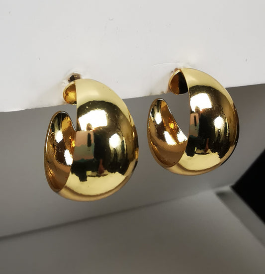 Boucles d'oreilles créoles larges dorées, 20mm de diamètre, 12mm de large, sur clous, Présentées accrochées l'une à coté de l'autre à un support , vue de gauche en gros plan.
