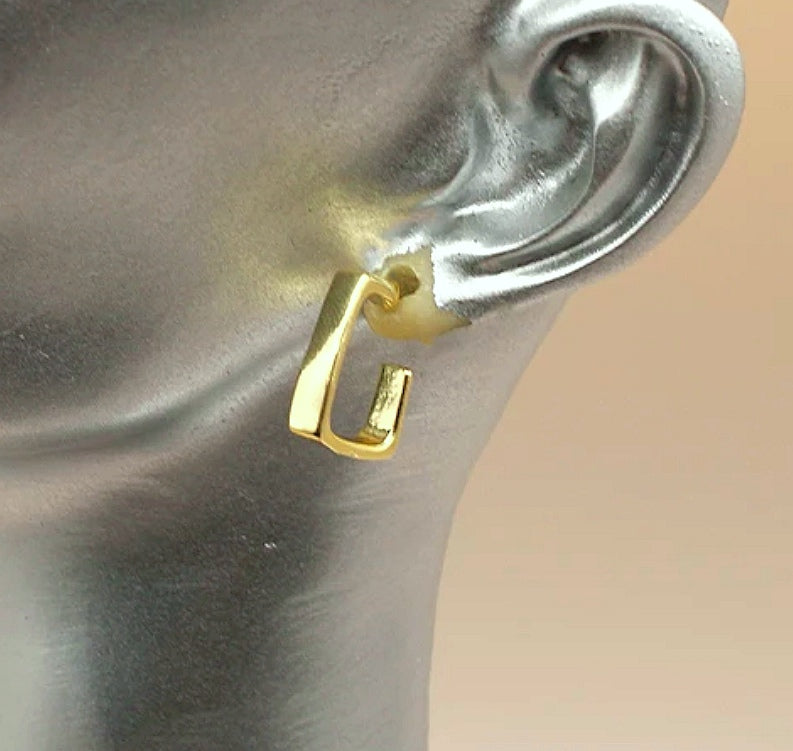 Une boucle d'oreilles dorées, carrées, de 15mm de coté ,avec section rectangulaire, présentées suspendue à l'oreille d'un buste gris. Vue de droite.